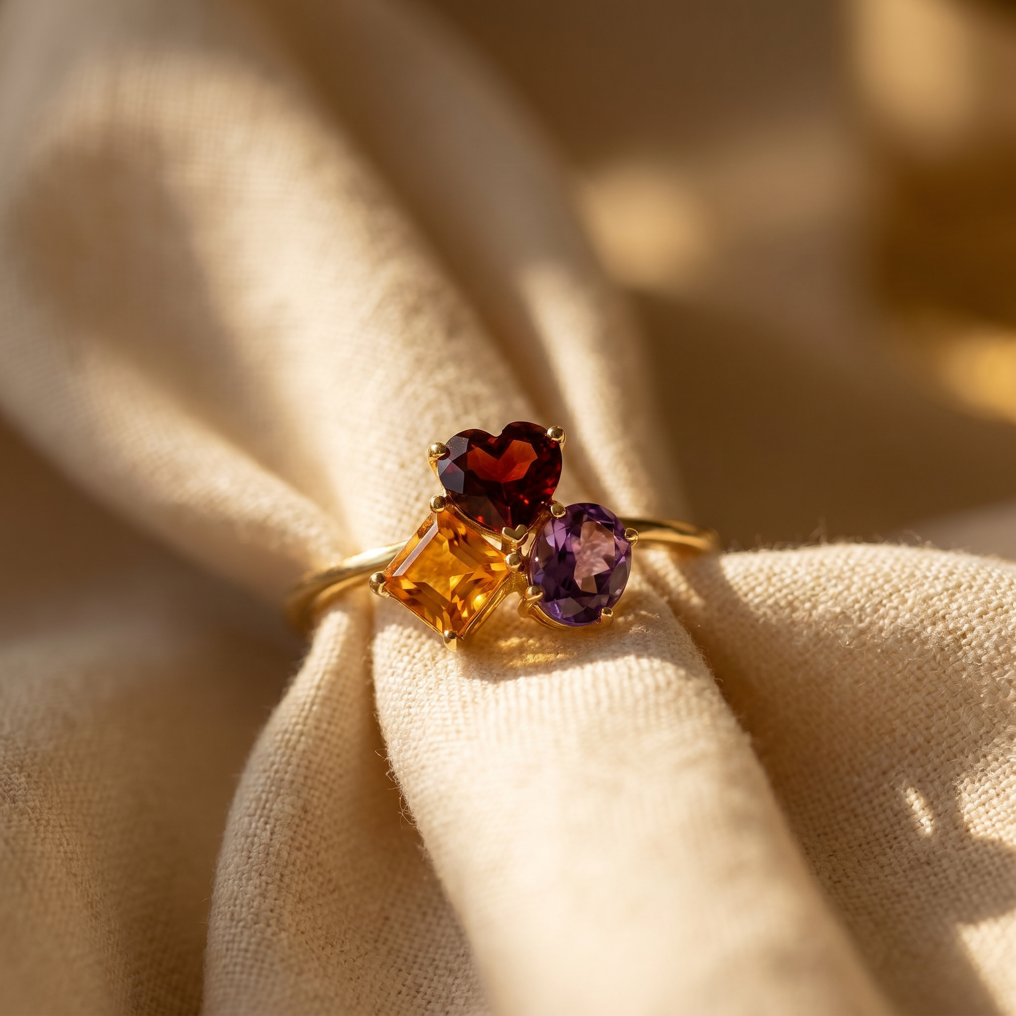 Garnet, citrine and amethyst ring in 18K yellow gold, editorial scene on warm linen