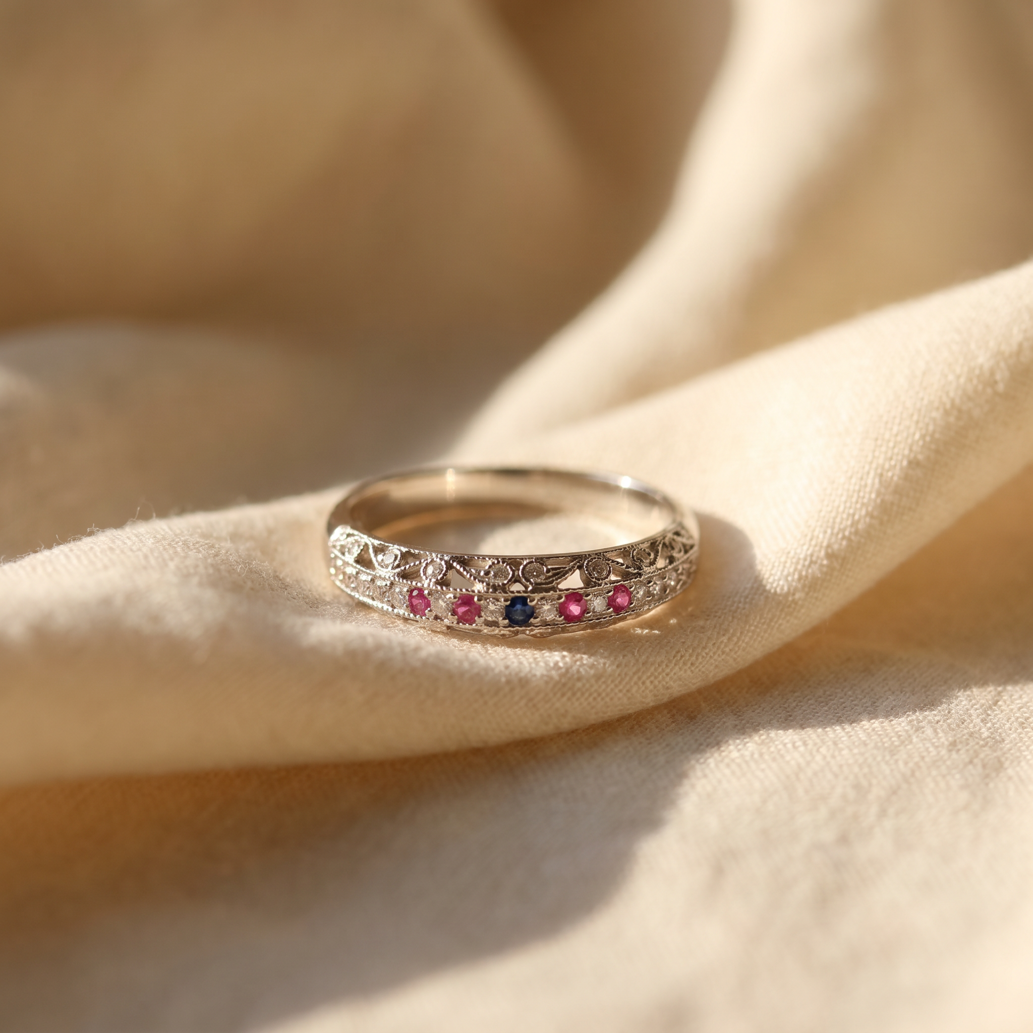 Vintage-inspired ruby multi-stone ring in 18K white gold, editorial scene on warm linen