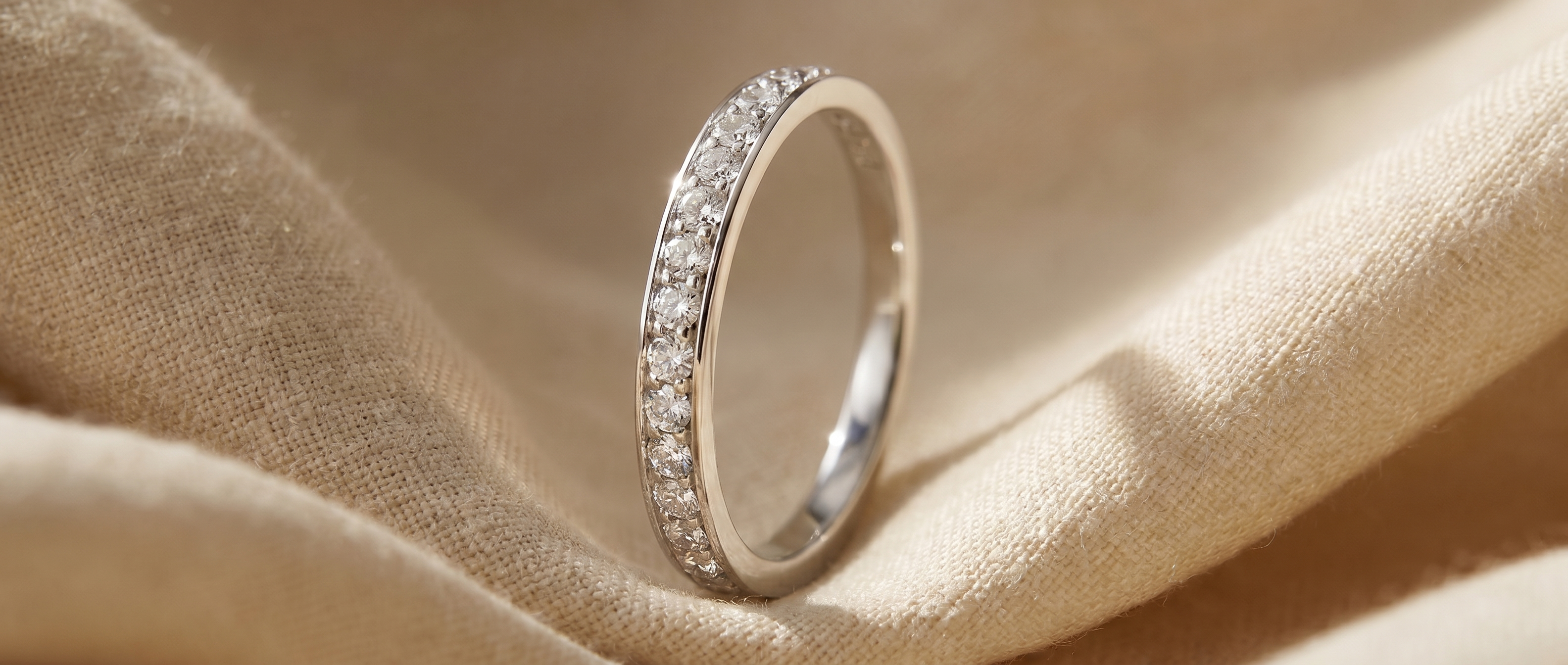 Diamond pavé eternity band on warm taupe linen — the Quiet collection