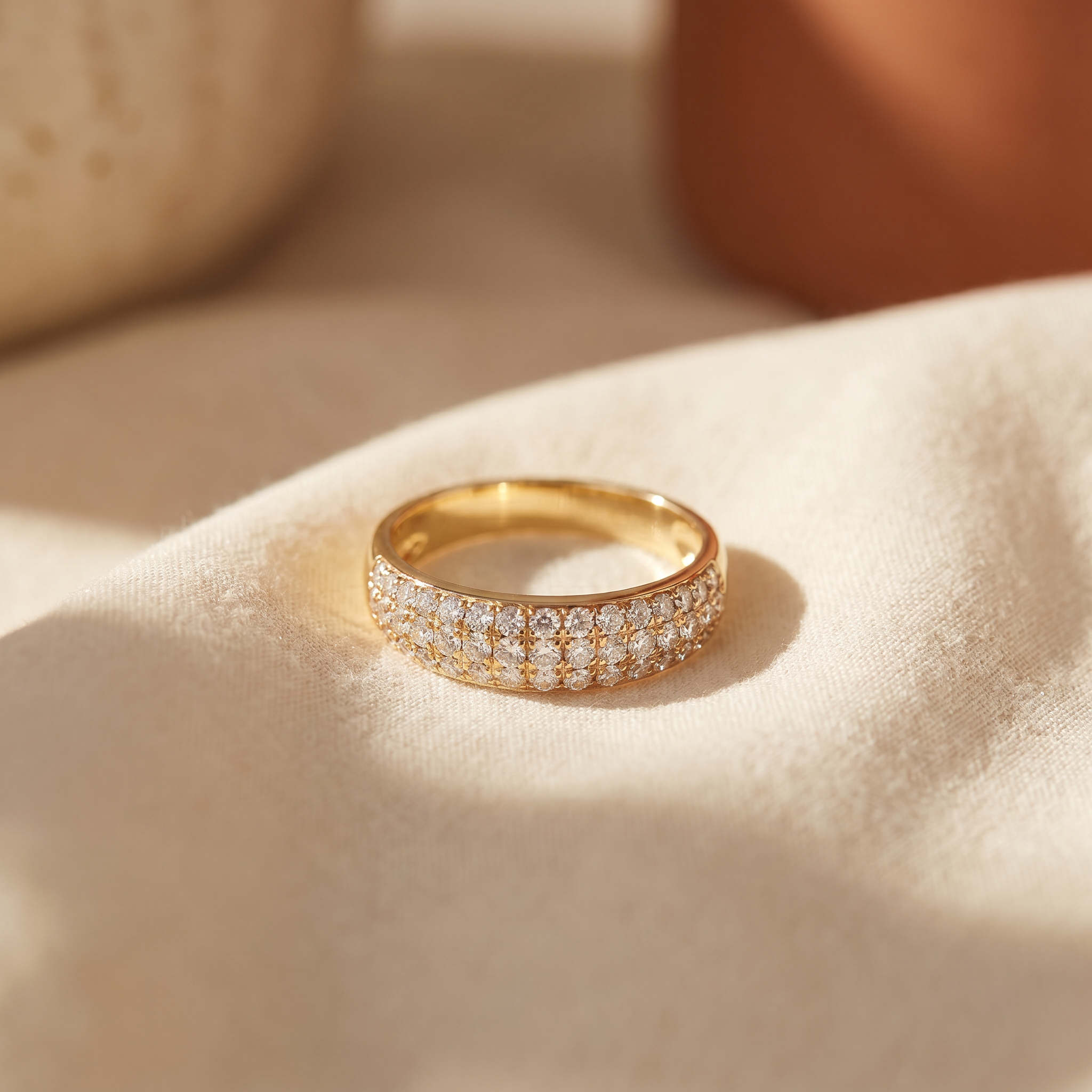 Multi-row diamond band in 18K yellow gold, editorial scene on warm linen