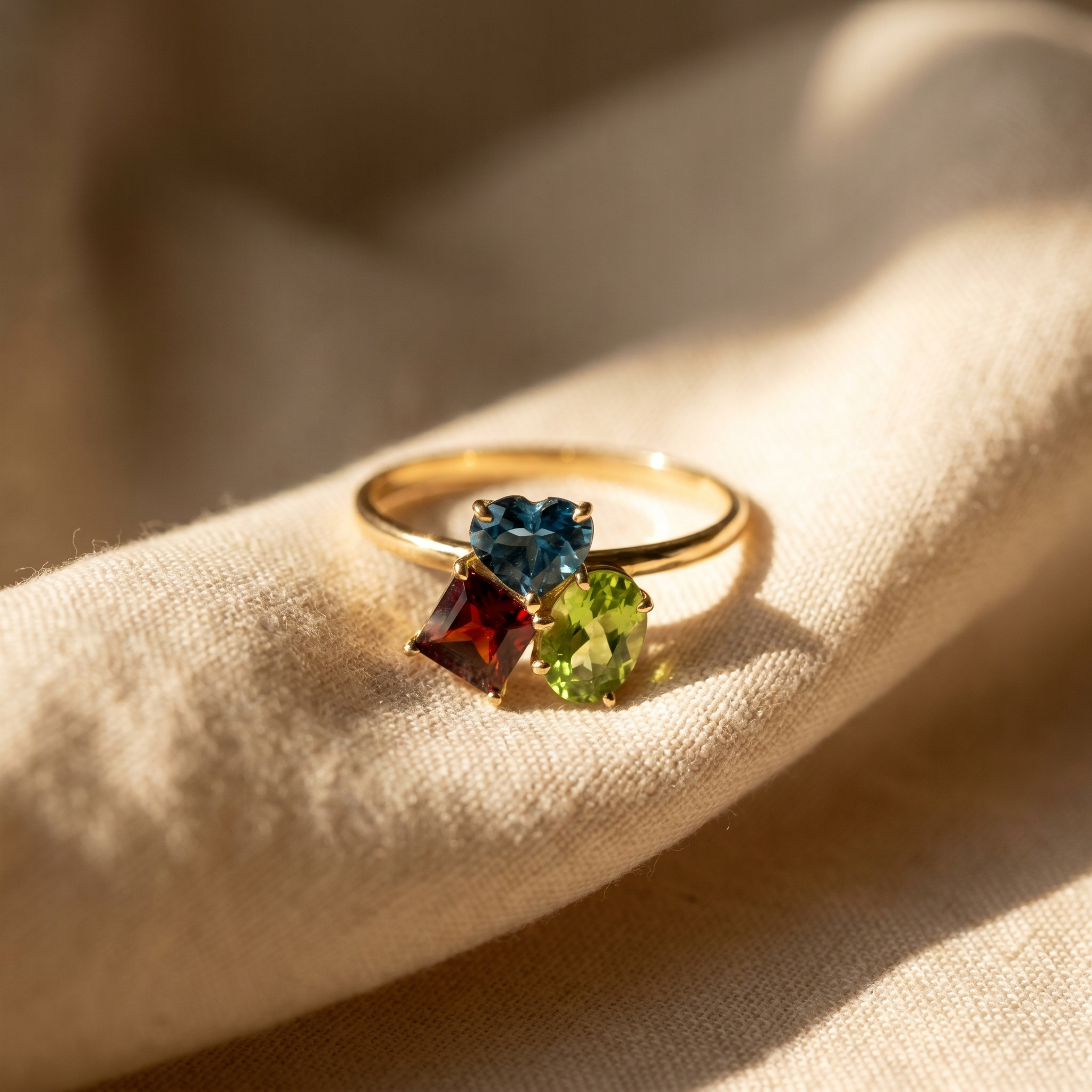 Topaz, garnet and peridot cluster ring in 18K yellow gold, editorial scene on warm linen