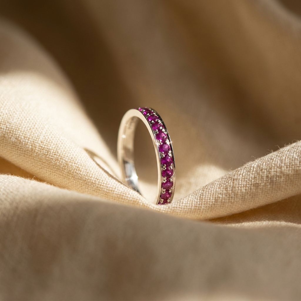 Purplish-red ruby eternity ring in 18K white gold, editorial scene on warm linen