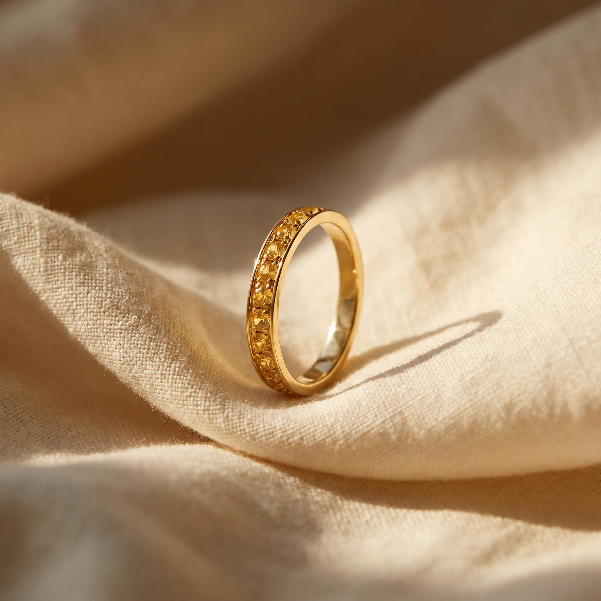 Golden yellow sapphire eternity ring in 18K yellow gold, editorial scene on warm linen