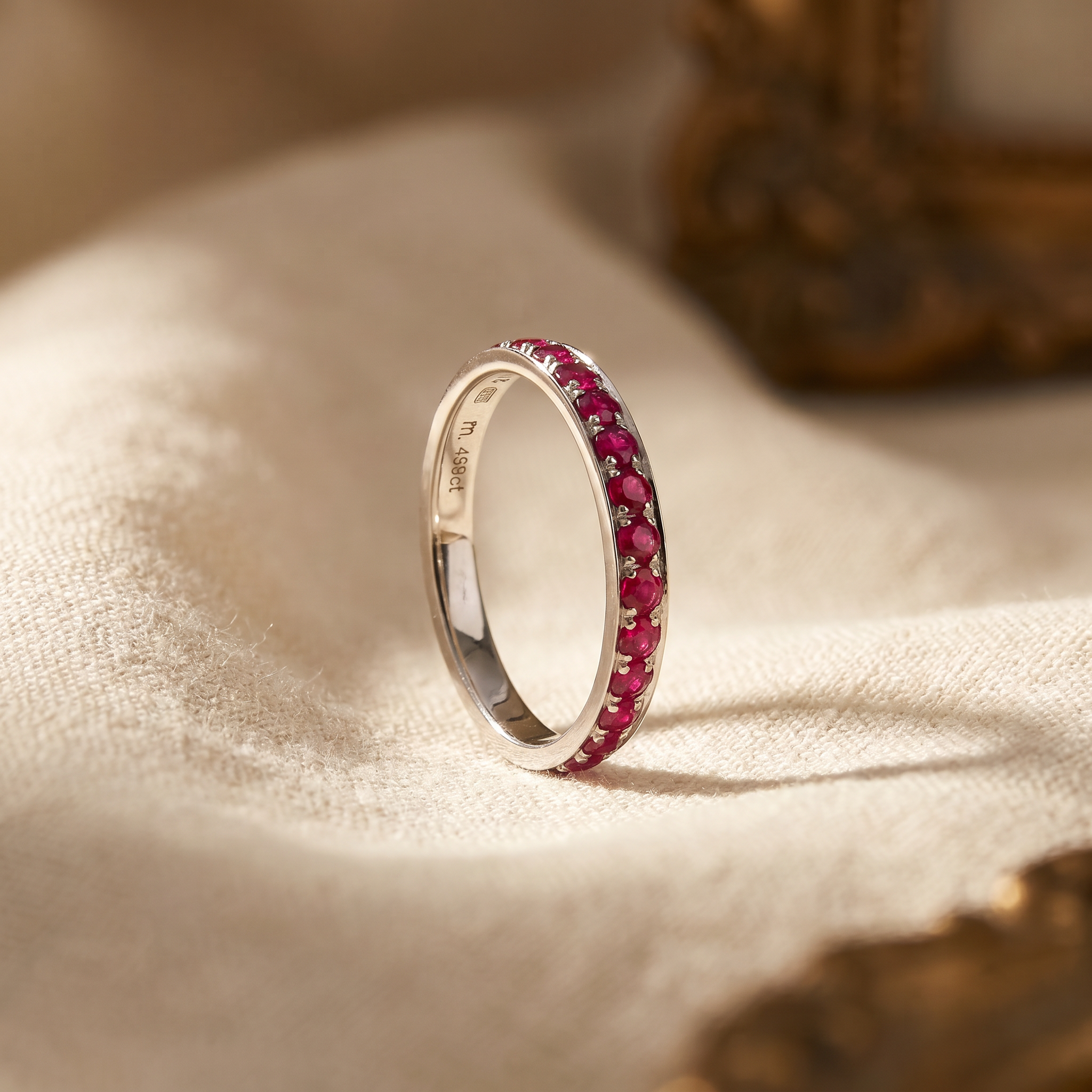Red ruby eternity ring in 18K white gold, editorial scene on warm linen